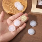 A close-up view of six round white silicone leak stoppers, neatly arranged, designed for water bottle and tumbler lids.